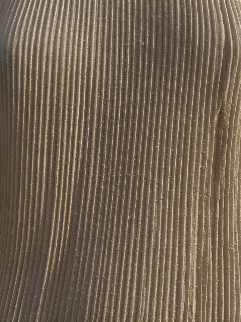 Detail — knife-pleated raw silk, grains of sand caught in the folds